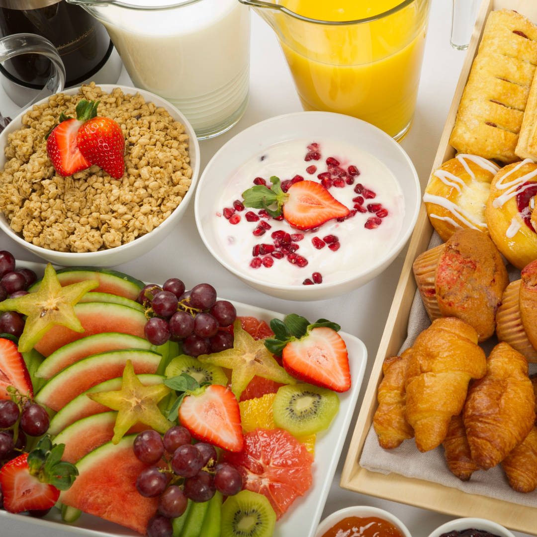 A table filled with fresh juices, pastries, homemade bread, fruit salad, and cereals for a continental breakfast.